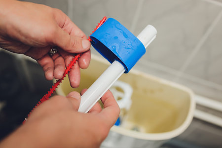 Hand is fixing a toilet cistern at home.の写真素材