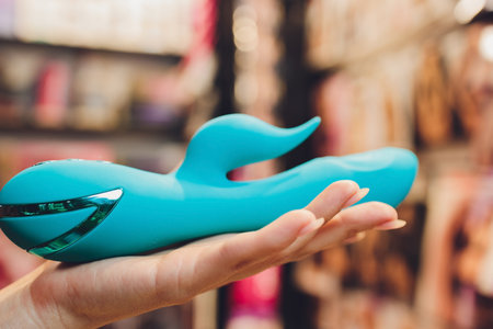 Girls hand holds a pink massager for sex. Vibrator for masturbation. Dildo for vaginal and clitoral stimulation. Image for sex shop. Sex toys for adults. Massager for the clitoris.の写真素材