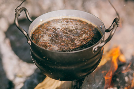 Hiking pot, Bowler in the bonfire. soup boils in cauldron at the stake. Traveling, tourism, picnic cooking, cooking at the stake in a cauldron, fire and smoke.の写真素材