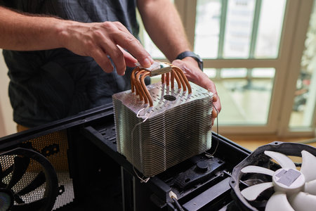 Internal parts of an old personal computer. Dusty motherboard, video card and fan. The master cleans the PC cooler from dust. Broken PC.の写真素材