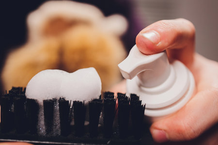 Hands cleaning mens camel suede desert shoe boot with a brush. Footwear maintenance captured from above top view.の写真素材