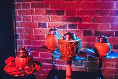 Red shisha hookah with smoke and red sparks on wood table brick, art background. Shisha Concept.