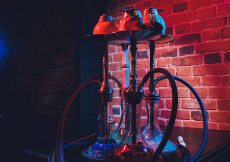 Red shisha hookah with smoke and red sparks on wood table brick, art background. Shisha Concept.