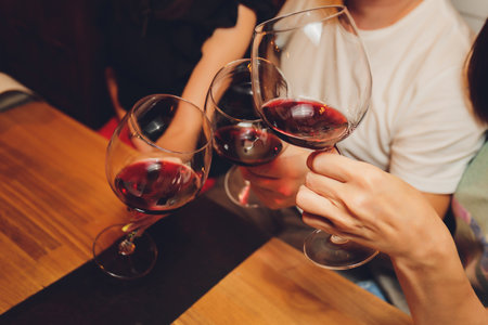 Close up shot of group of people clinking glasses with wine or champagne in front of bokeh background. older people hands.の写真素材
