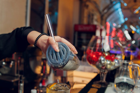 Bartender making a cocktail with thin slices of fresh orange fruit on the background of bar counter.の写真素材