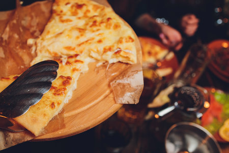 Azerbaijani restaurant dish with vegetable decor on a wooden background. Khachapuri in Megrelian on the Board.の写真素材