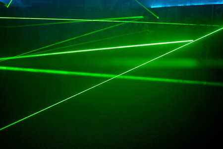 Bright green neon laser lights illuminate the darkness creating lines and triangle shapes in sci-fi effect.の写真素材