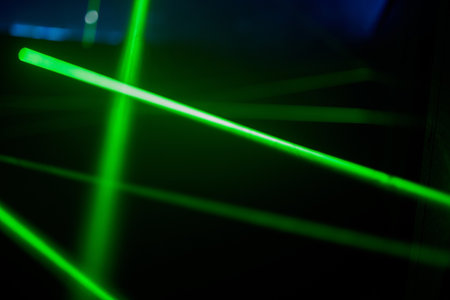 Bright green neon laser lights illuminate the darkness creating lines and triangle shapes in sci-fi effect.の写真素材
