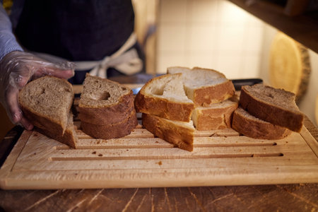 Male hands cutting wheaten bread on the wooden board, selective focus.の写真素材