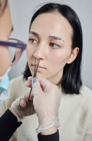 Closeup of a young womans visage with piercing septum hanging from her nose.の写真素材