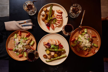 Friends having dinner. Top view of four people having dinner together while sitting at the rustic wooden table.の写真素材