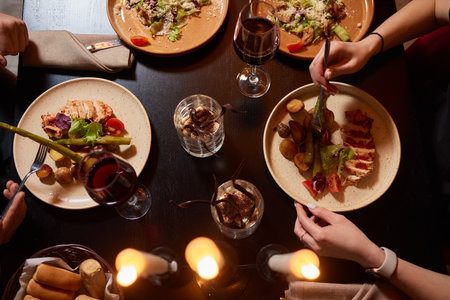 Friends having dinner. Top view of four people having dinner together while sitting at the rustic wooden table.の写真素材