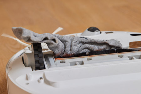Robotic vacuum cleaner performs cleaning of the room, where socks laying on the floor. Smart...