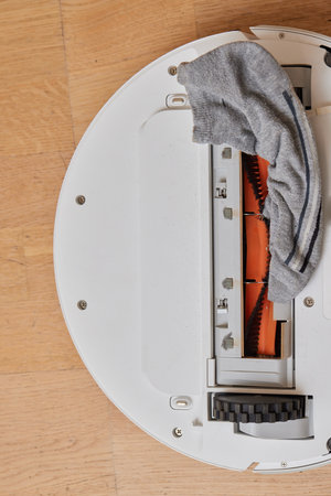 Robotic vacuum cleaner performs cleaning of the room, where socks laying on the floor. Smart cleaning technology.の写真素材