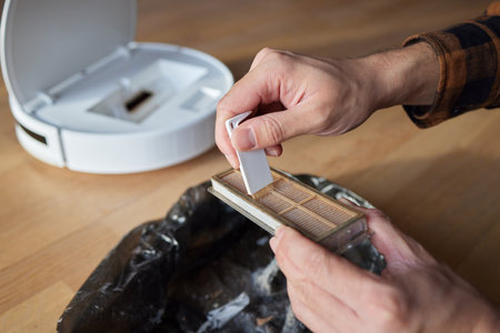 Cleaning the filter of the vacuum robot cleaner from dirt, close-up.の写真素材