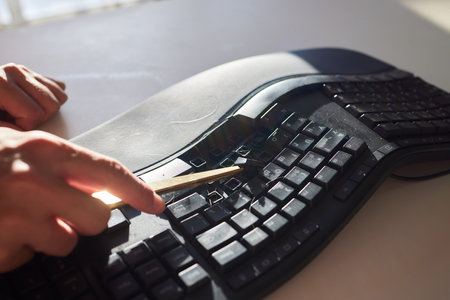 Old dirty computer keyboard with removed keys. The tools for repair and cleaning on the table in the workshop workspace.の写真素材
