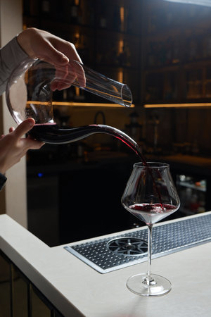Sommelier man pours red wine into decanter for aeration of taste and aroma.の写真素材