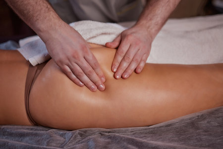 Anti-cellulite massage in the spa salon. The masseur massages the buttocks, thigh and legs. Relaxing treatment. Slimming and body shaping. Healthy body and skin. Self love care.の写真素材
