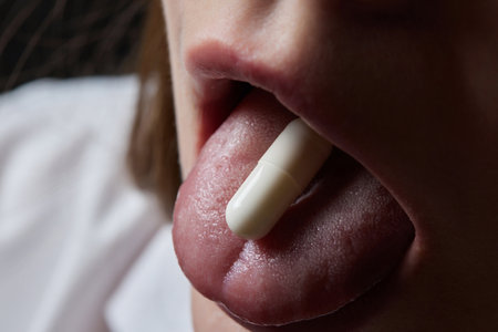 Close up of face of young woman taking drug. The drug addict is standing and putting a pill into her mouth.の写真素材