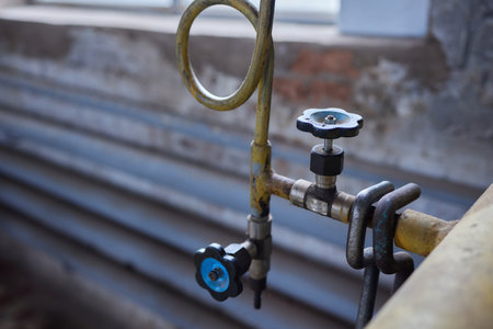 Close-up at pipeline valve which is using to control production process in the oil refinery plant. Selective focus at the valve handle wheel, Heavy industrial object photo.の写真素材