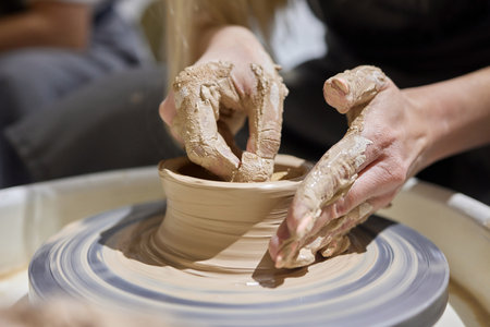 Close up shot of hands of crafts people, working with clay in pottery studio.の写真素材