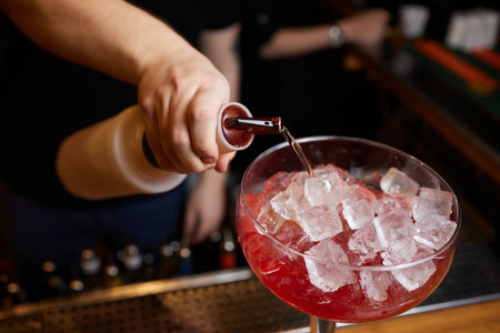 Bartender is making cocktail at bar counter at night club, Close Up. Concept about service and...