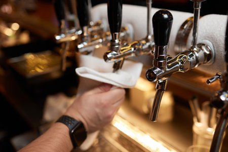 Waiter or bartender cleaning beer taps on the counter in pub and restaurant.の写真素材