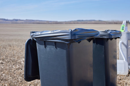 Trash bin on a field with garden weeds to be cleaned up.の写真素材