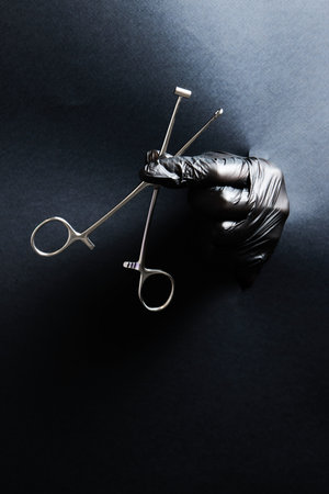 hand-held stainless steel surgical scissors with gloves.