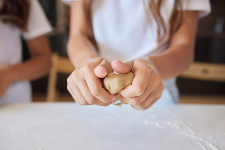 Close up image woman and little daughter knead dough with hands wooden table powdered with flour.の写真素材