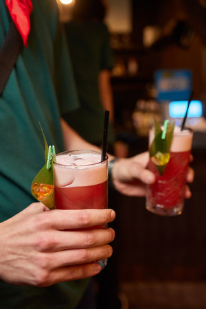 Bartender dressed in black apron and shirt make red cocktail drink on black background