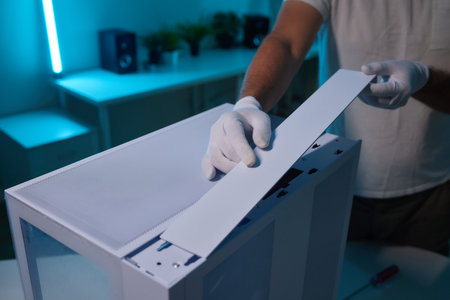 Rear view of a young man installing graphics card to his desktop computer at home.の写真素材