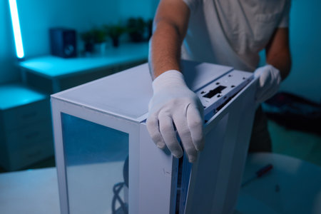 Rear view of a young man installing graphics card to his desktop computer at home.の写真素材
