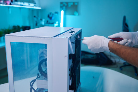 Rear view of a young man installing graphics card to his desktop computer at home.の写真素材