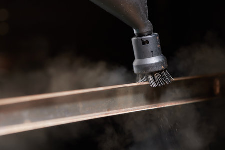 Experienced worker in rubber gloves steam-cleaning kitchen equipment.の写真素材