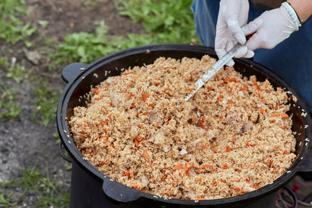 Cooking food or pilaf in a cauldron on fire. Cooking in cauldron on open fire in nature. Bowler on...