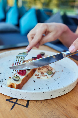 Female hand holds a piece of cottage cheese casserole with the cake server. Cheese pie with...