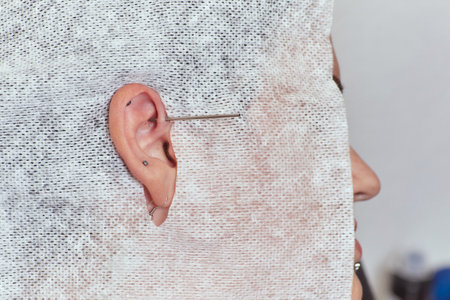 piercings on an ear. Conch and helix piercings close up. Professional holding the jewel.の写真素材