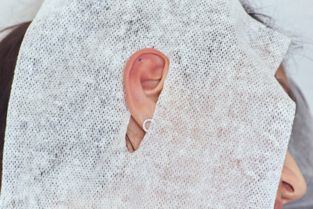 piercings on an ear. Conch and helix piercings close up. Professional holding the jewel.の写真素材