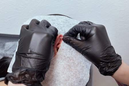 piercings on an ear. Conch and helix piercings close up. Professional holding the jewel.の写真素材