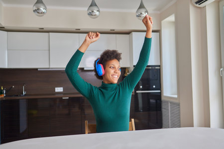 Overjoyed millennial girl wearing headphones have fun moving listening to music relax in living room, happy young woman in earphones dance enjoy leisure weekend at home, stress free conceptの写真素材