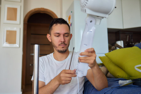 Mature man works to install a paddle fan on the ceiling at homeの写真素材