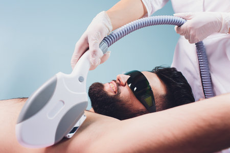 Men lying at beauticians during laser armpit hair removal therapy.の写真素材