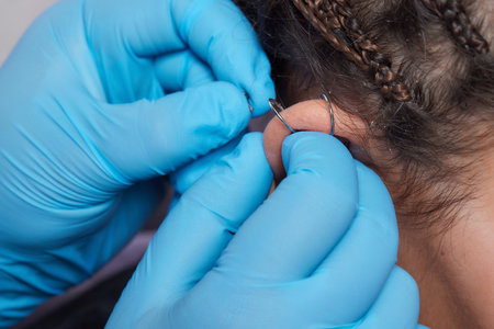 Professional placing the jewel of piercing on the temple on the head with ball. Tragus type.の写真素材