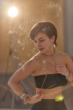 Beautiful mindfulness young girl relaxing and enjoying incense stick after yoga class.
