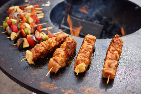 Round grill in the shape of a bowl with fire inside. A man prepares a hearth for barbecue. The round hearth is cleaned before cooking. The firewood lies in the bowl of the outdoor hearth.の写真素材