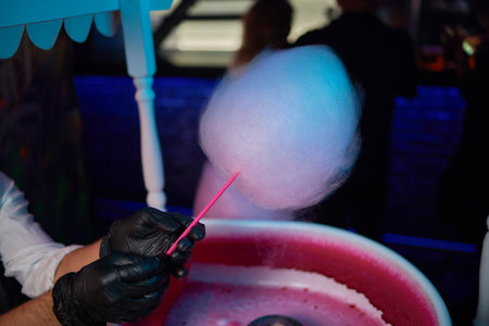 Hand rolling cotton candy in candy floss machine. Making candyfloss