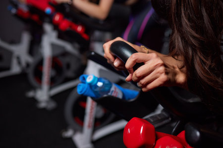 Close-up of hands of a man biking in the gym, exercising legs doing cardio workout cycling bikes. Couple in a spinning class wearing sportswear.の写真素材