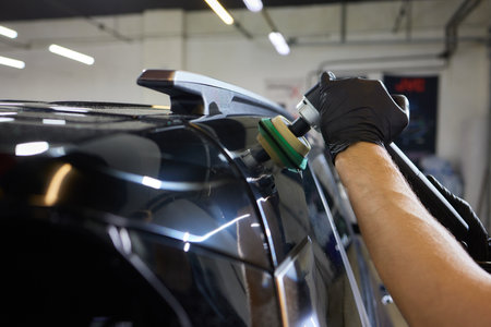 Man with an orbital polisher in car workshop polishing car closeupの写真素材
