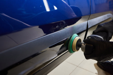 Man with an orbital polisher in car workshop polishing car closeupの写真素材
